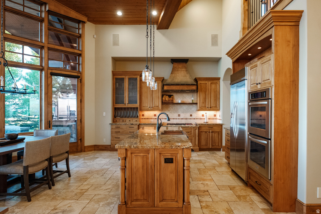 Kitchen and dining area featuring a central island with a granite countertop, stainless steel appliances, and wood-finish cabinetry