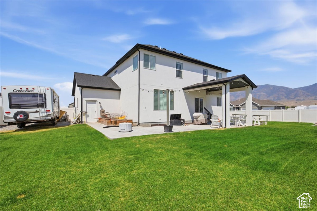 Modern two-story home with clean-lined exterior, featuring a covered rear porch, expansive manicured lawn, and mountain backdrop