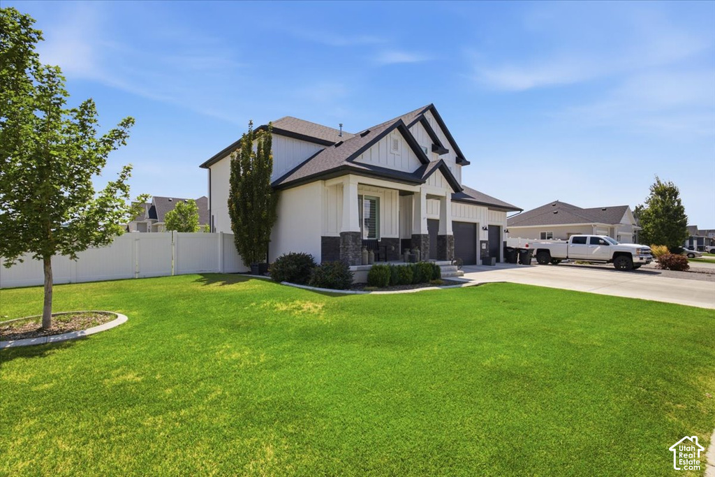 Modern farmhouse exterior with white vertical siding and dark gray stone accents, featuring a deep front porch and a two-car garage