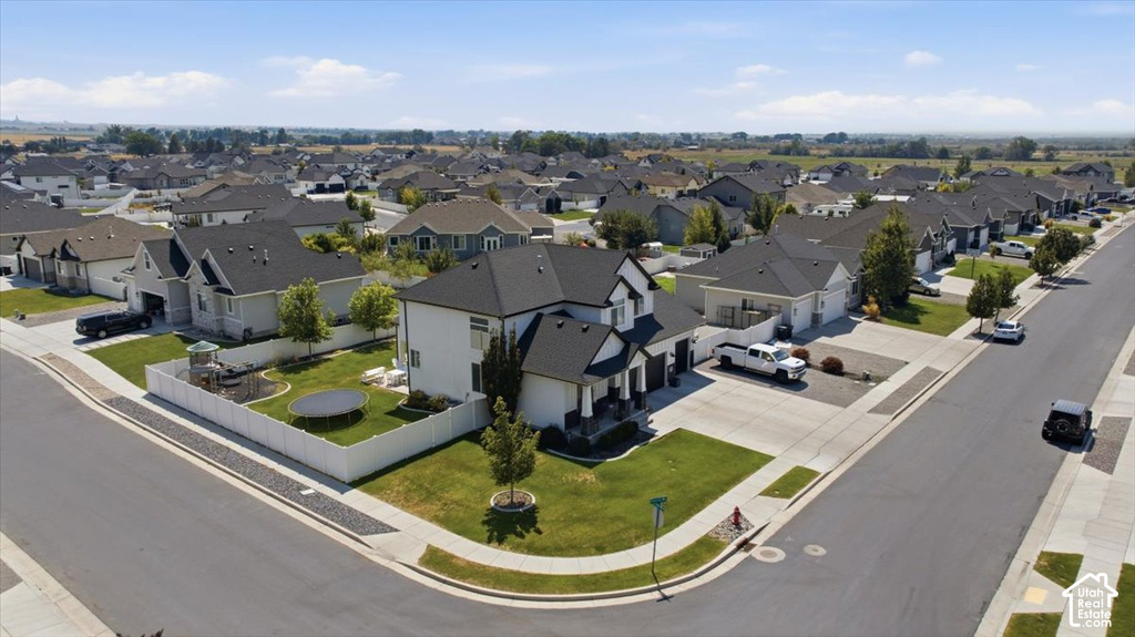Corner lot property featuring a white privacy fence, manicured lawn, and a paved driveway
