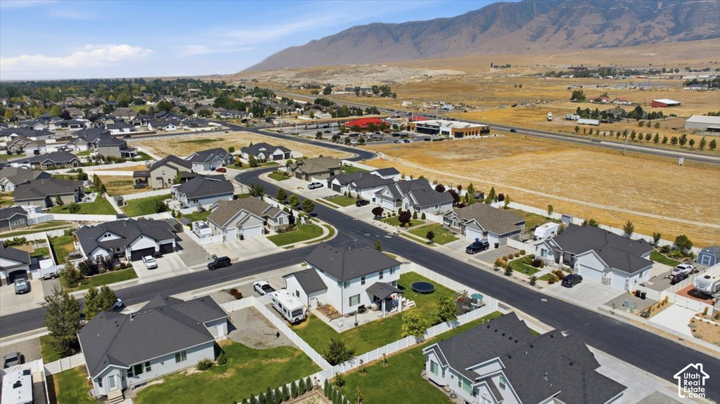 Aerial view of a new residential community featuring modern homes with clean architectural lines, dark asphalt roofing, manicured landscaping, and wide paved streets