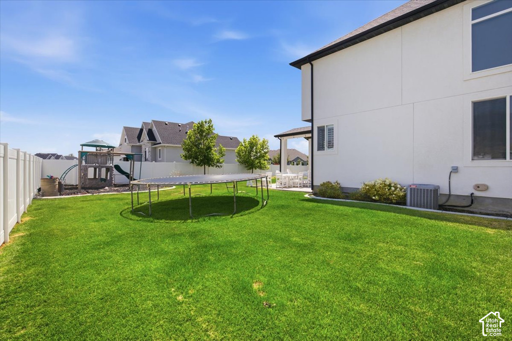 Expansive backyard featuring a large lawn, white privacy fencing, and a covered patio area