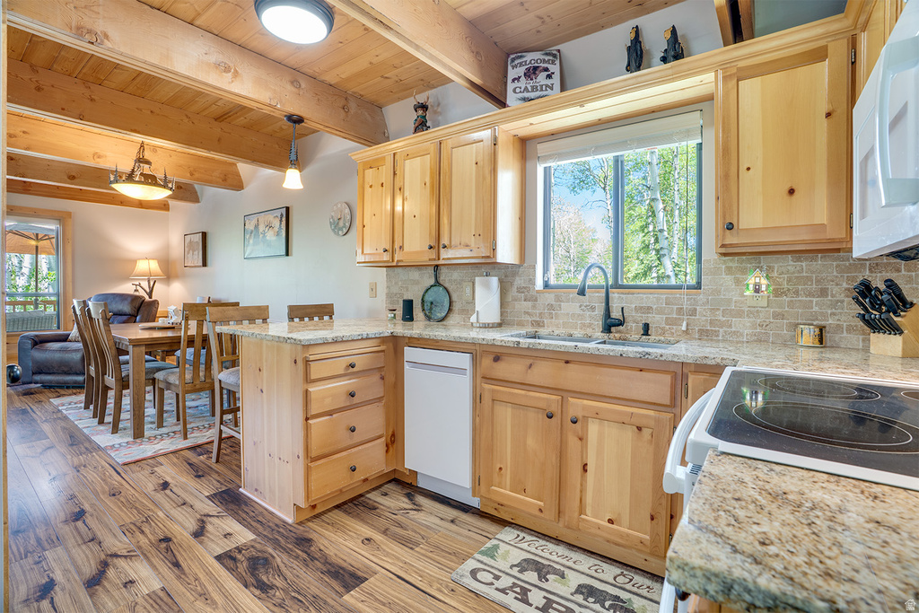 Kitchen featuring wood-finish flooring, exposed wood beam ceiling, natural wood cabinetry, light-toned stone countertops, and a full-height tile backsplash