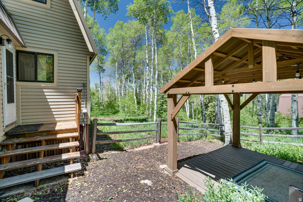 Outdoor living area featuring a wood-beam pergola with integrated lighting, composite decking, and a fenced perimeter