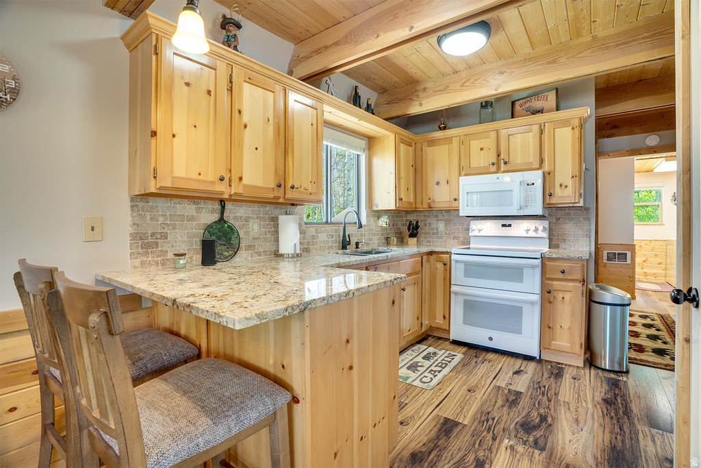 Kitchen featuring light wood cabinetry, granite-style countertops, mosaic tile backsplash, and wood-finish flooring