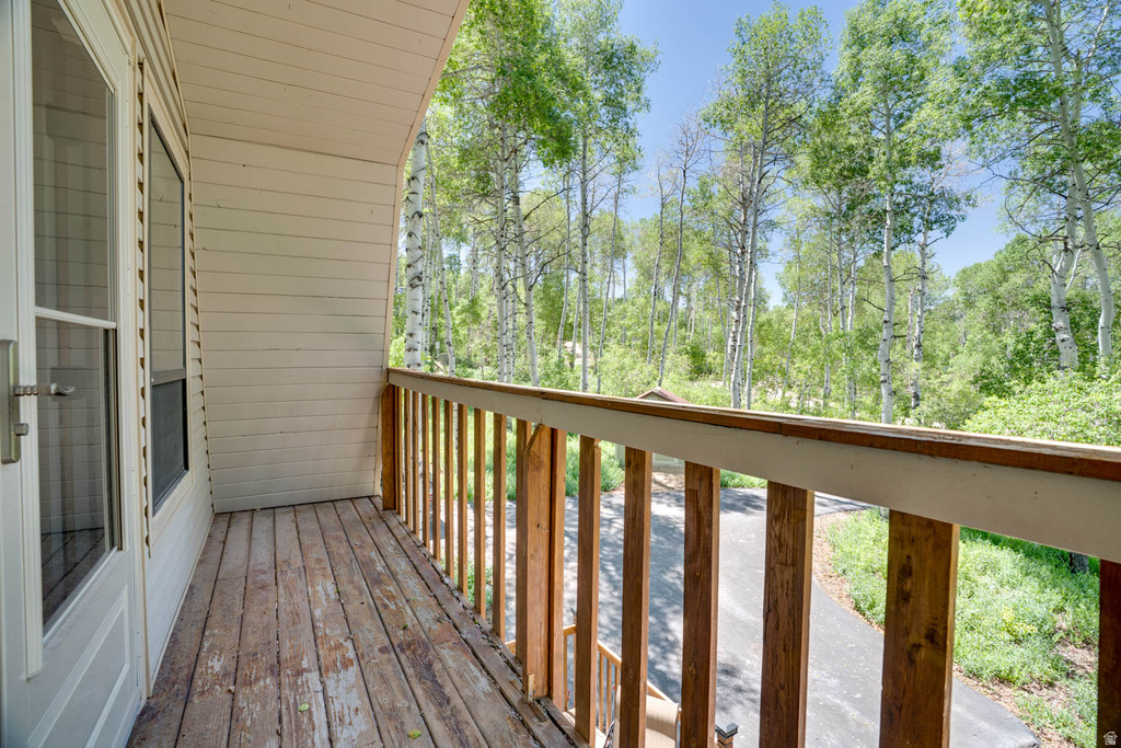 Exterior balcony featuring a wood-plank floor and natural wood railing