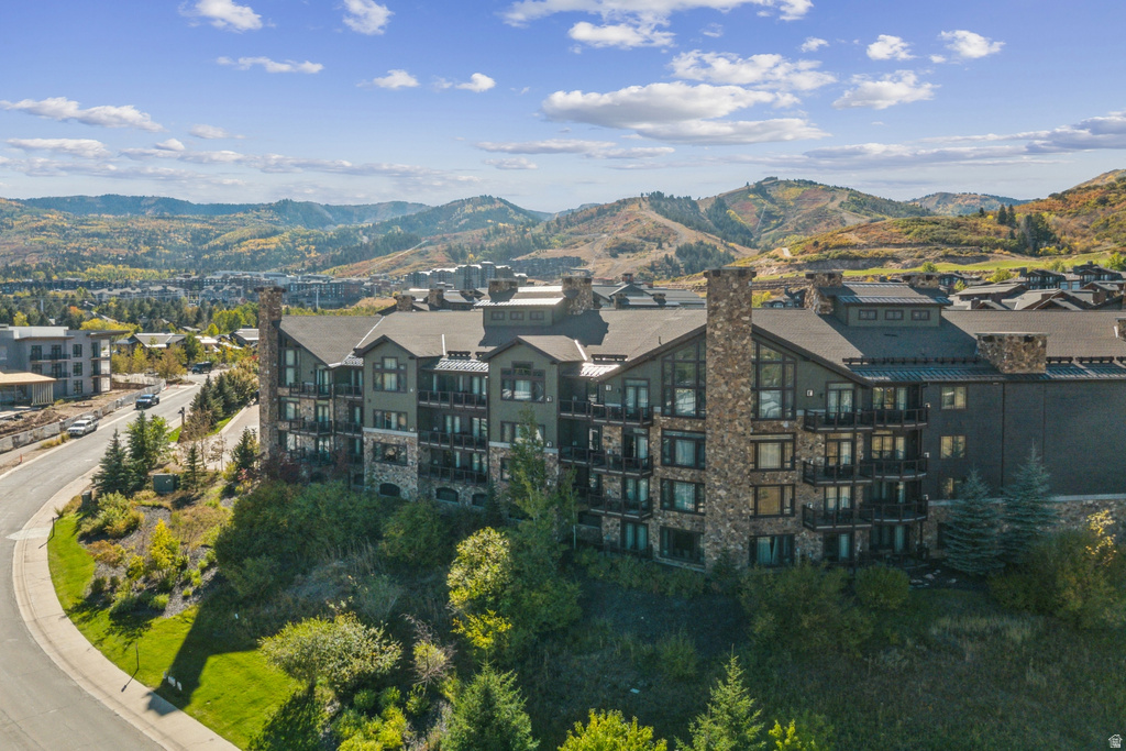 Multi-story building featuring stone and dark siding exteriors, a prominent stone chimney, multiple private balconies, and a sloped roofline