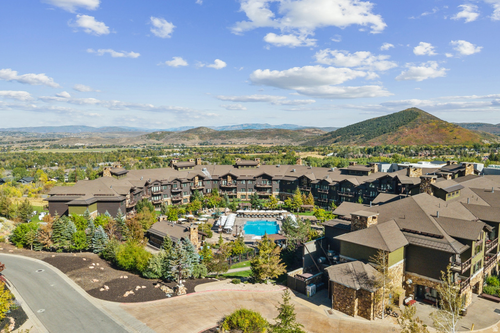 Extensive resort-style property featuring multiple buildings with stone and siding exteriors, a large outdoor swimming pool, surrounding lounge areas, mature landscaping, and mountain backdrops