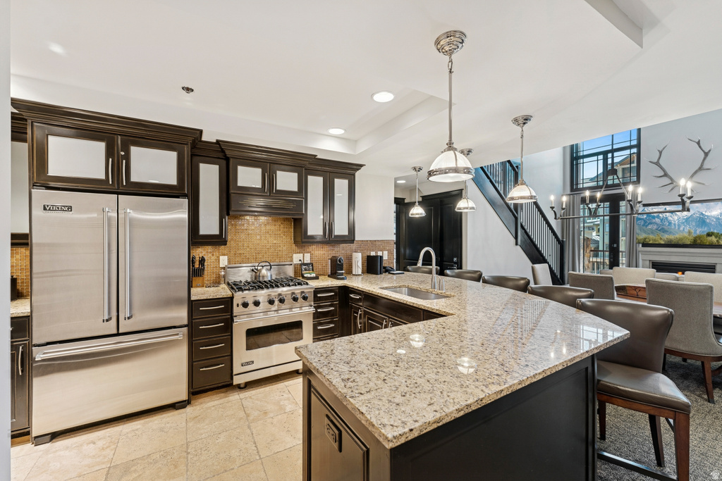 Gourmet kitchen with an expansive island featuring a light-toned countertop, a stainless steel sink, and pendant lighting