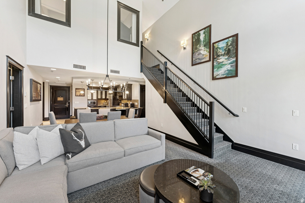 Two-story living area featuring a vaulted ceiling and a prominent staircase with dark wood-finish newel posts and railings