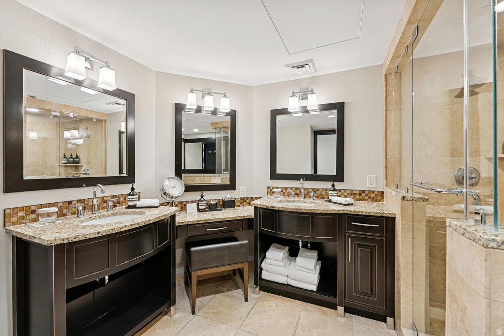 Dual dark wood-finish vanities with light stone countertops, mosaic tile backsplash, framed mirrors, and chrome fixtures