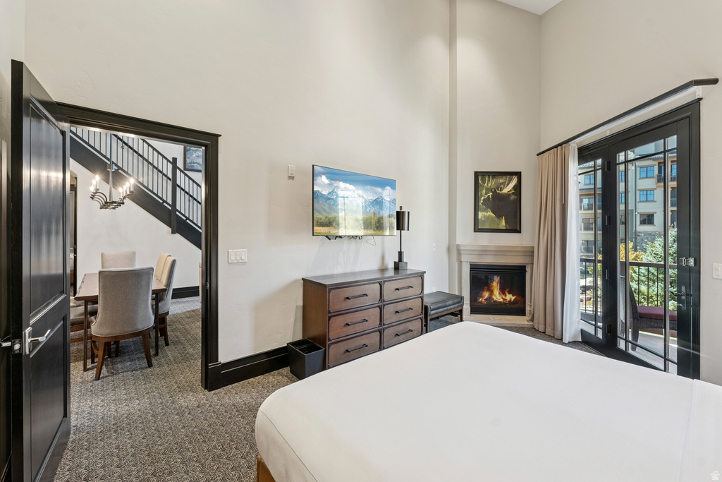 Spacious room with high ceilings, featuring a corner fireplace with a stone-finish mantel, and large glass-paned double doors opening to a balcony
