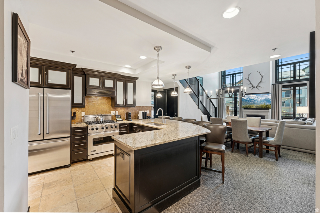 Open-concept kitchen featuring dark wood cabinetry, stainless steel appliances, and a granite-top island with seating