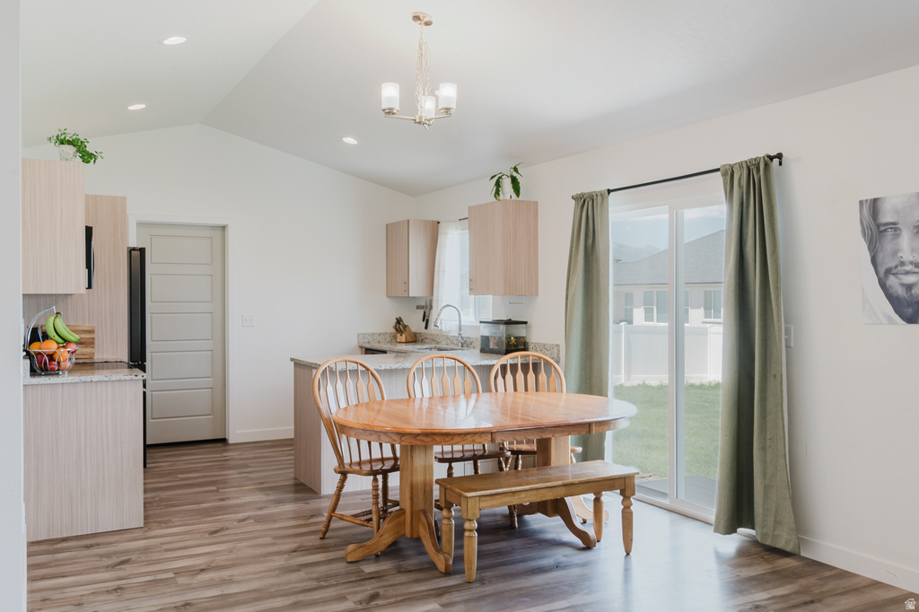 Vaulted ceiling kitchen and dining area featuring wood-finish flooring
