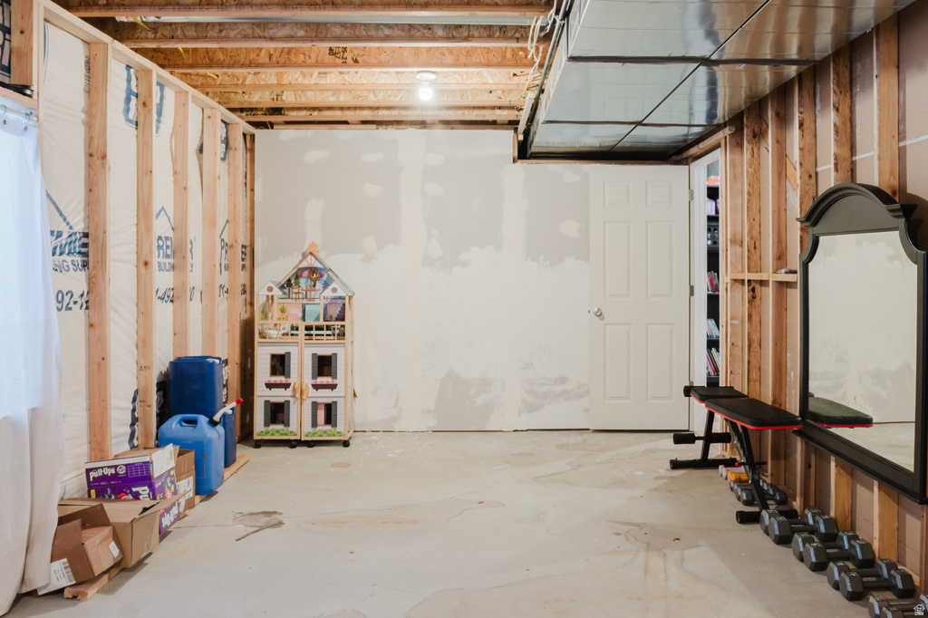 Unfinished basement space featuring exposed wood framing, concrete flooring, and exposed ceiling joists