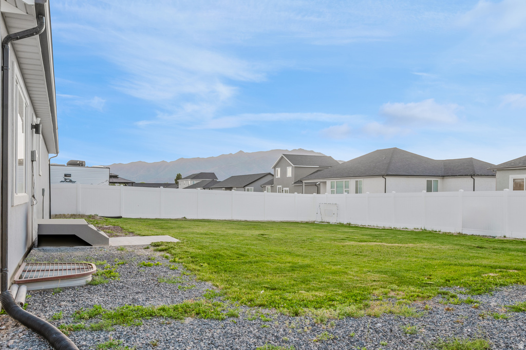 Expansive grassy yard area with a white privacy fence