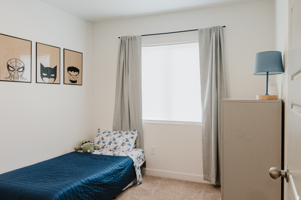 Carpeted room featuring a single window with blinds and curtains, painted white walls, and a recessed ceiling