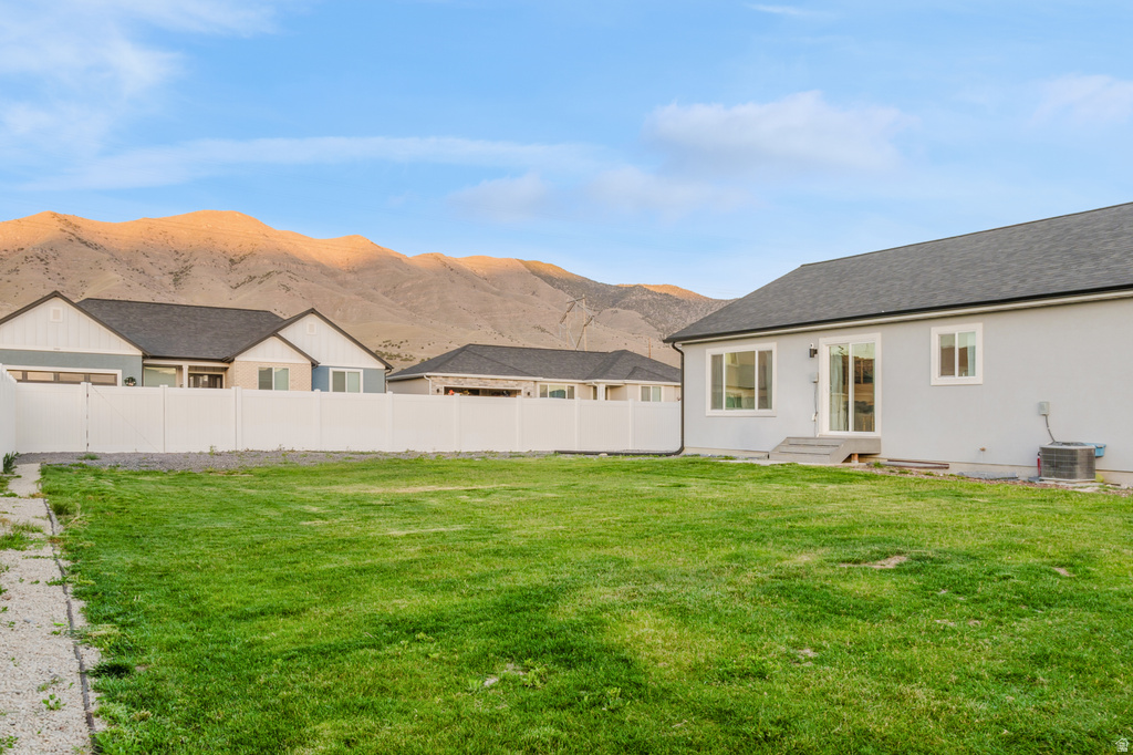 Spacious backyard featuring a manicured lawn, a white privacy fence, and mountain scenery