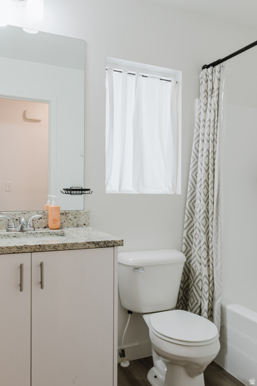 Bathroom featuring a vanity with a light-toned speckled countertop, light-colored cabinetry with brushed nickel hardware, and wood-finish flooring