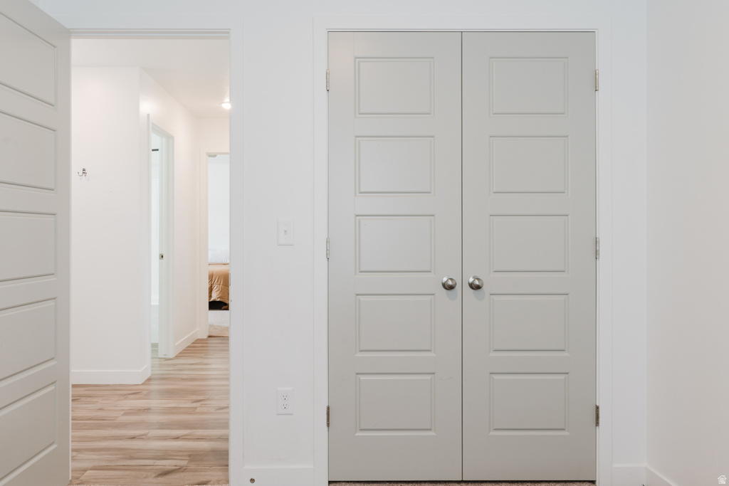 Panel-style bifold doors with chrome hardware, wood-finish flooring, white baseboards, and white wall finishes