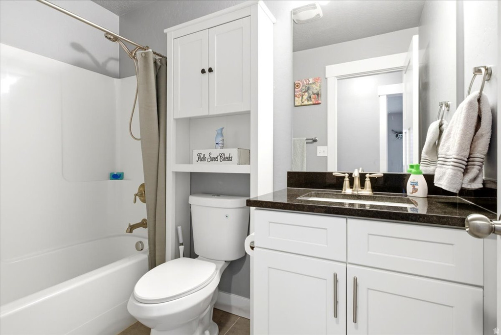 Bathroom featuring a white vanity with shaker-style cabinetry, a dark countertop, and an undermount sink
