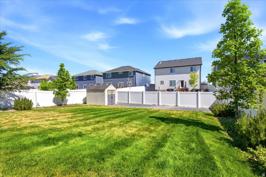 Expansive backyard featuring a manicured lawn, a white privacy fence, and a storage shed