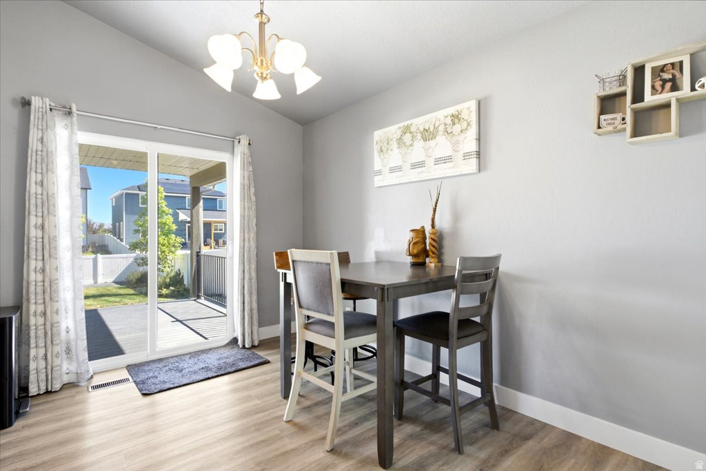 Dining area featuring wood-finish flooring, a contemporary chandelier, and light gray walls
