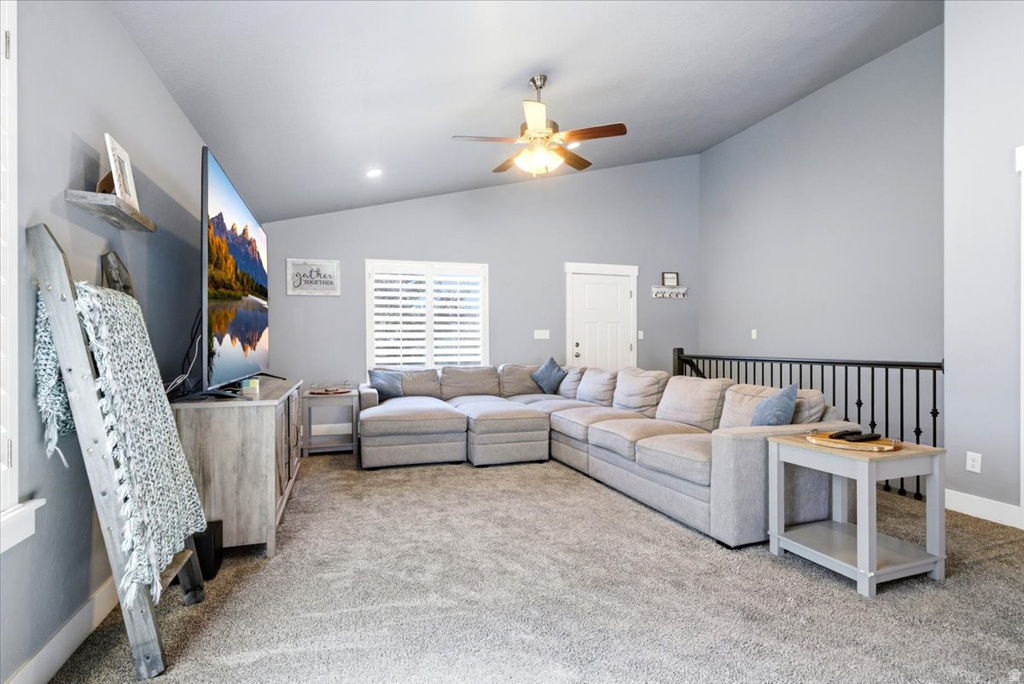 Spacious living area featuring a vaulted ceiling with a ceiling fan, light gray wall paint, and plush gray carpeting