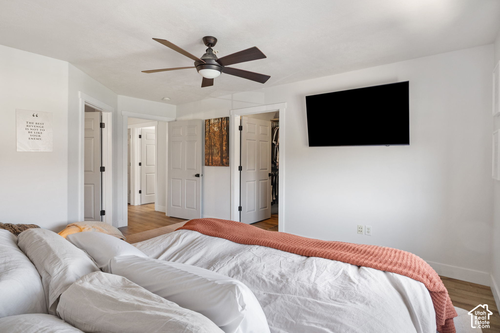 Bedroom featuring wood-finish flooring, white paneled doors, and a ceiling fan with integrated lighting