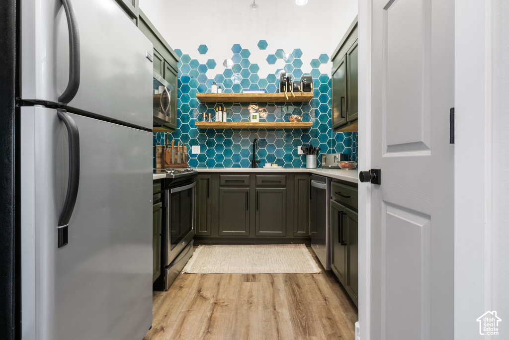 Galley kitchen featuring wood-finish flooring, dark cabinetry, and light countertops