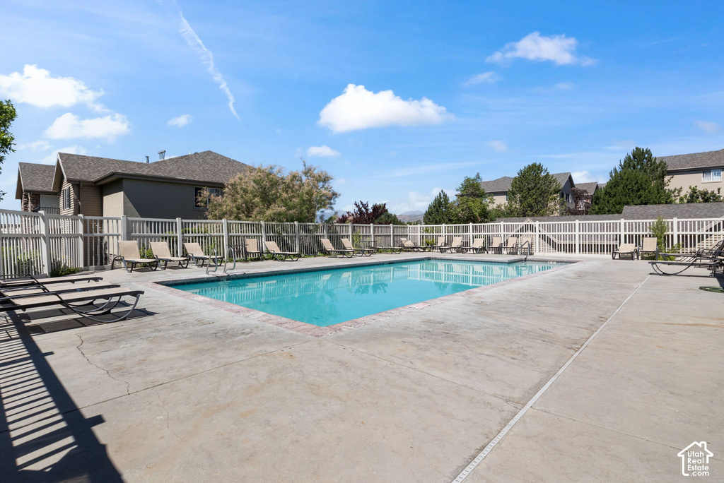 Rectangular swimming pool surrounded by a concrete deck and white fencing