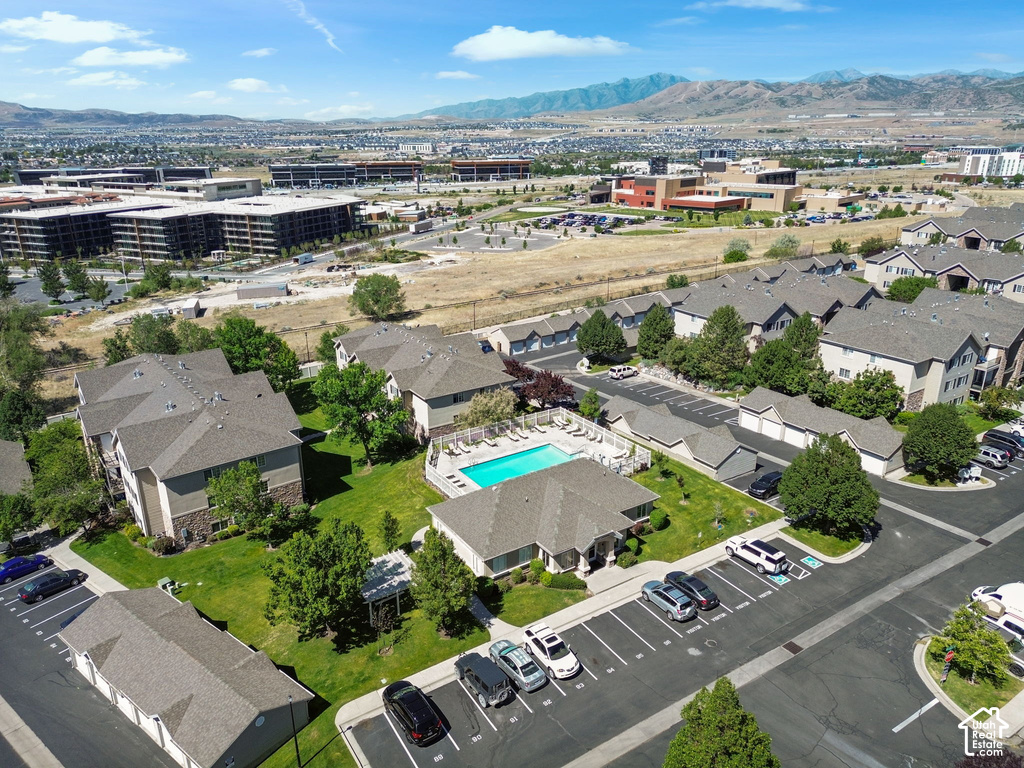 Expansive aerial view showcasing residential buildings with gray shingle roofs, a central swimming pool with surrounding patio, and dedicated parking areas