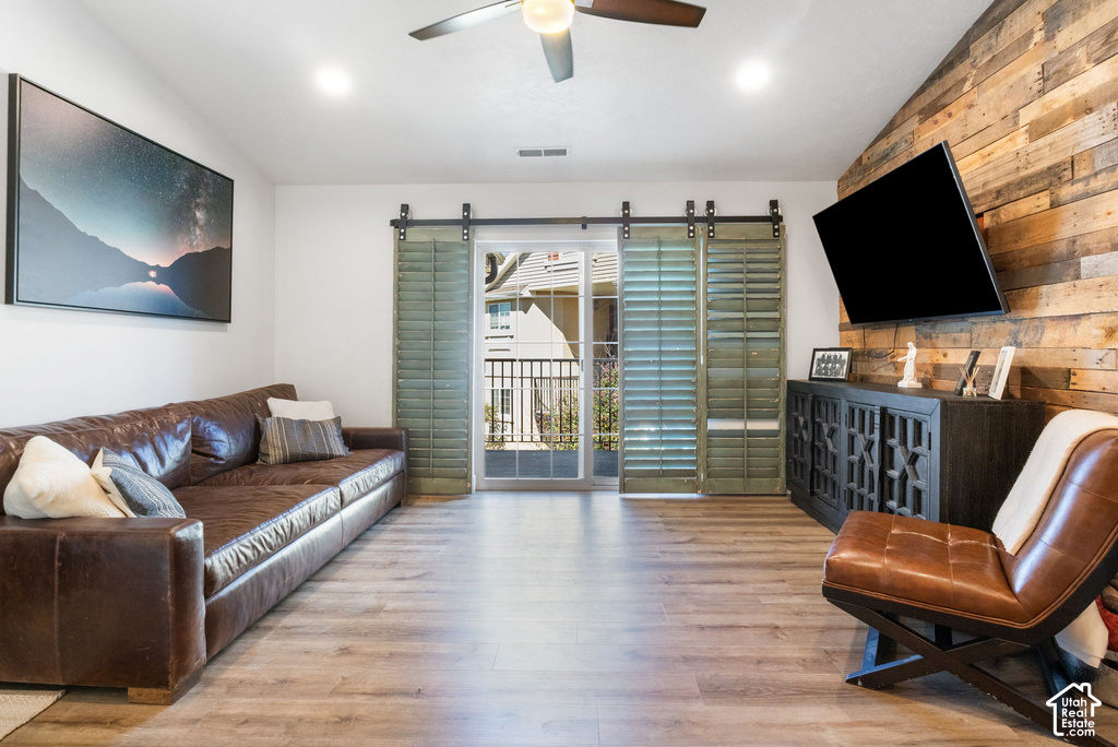 Living area featuring wood-finish flooring, a wood plank accent wall, and sliding glass doors to a balcony