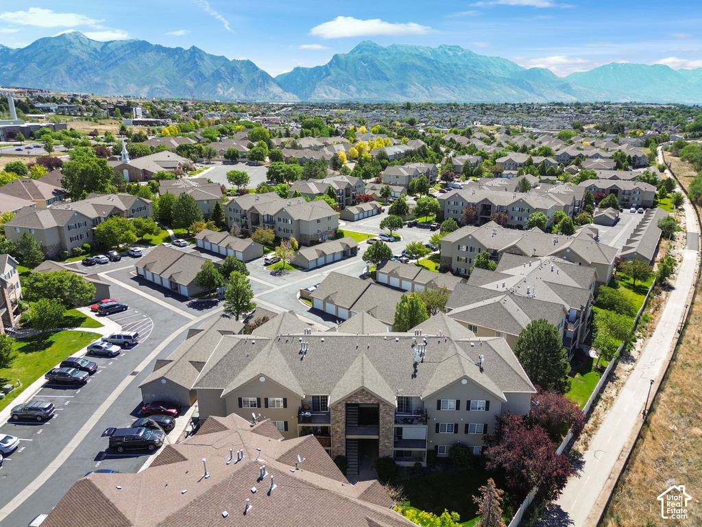 Expansive aerial showcasing a community of multi-story residential buildings with pitched roofs, surrounded by mature trees and manicured green spaces