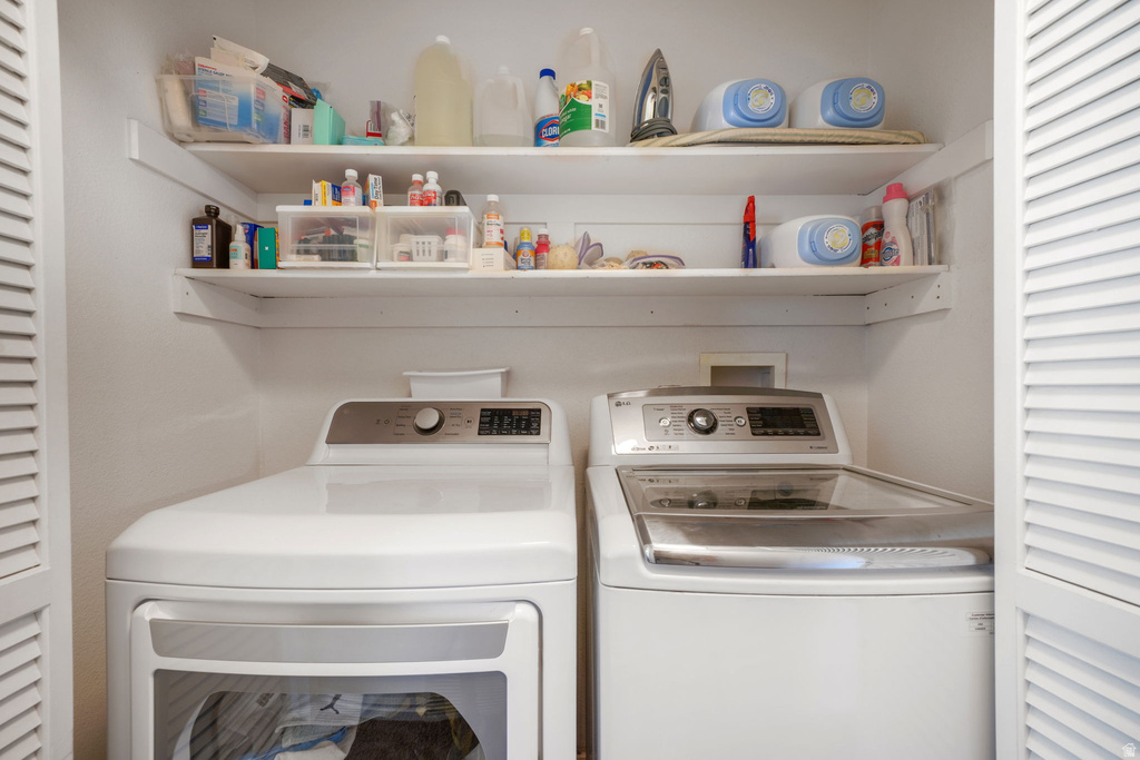 Laundry area featuring a side-by-side washer and dryer, integrated shelving, and louvered bifold doors
