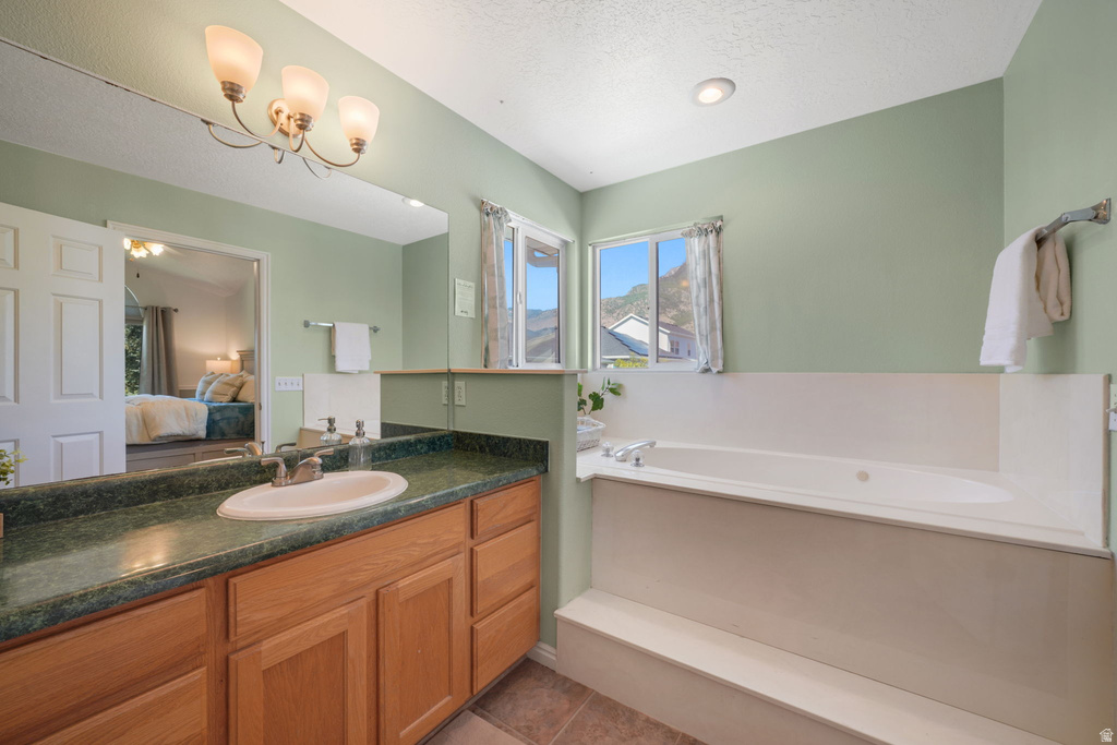 Bathroom featuring a built-in soaking tub, wood-finish vanity with an integrated sink, and an extensive mirror