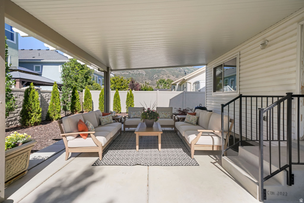 Spacious covered patio featuring a concrete surface, white siding, black metal railing, and a stone retaining wall