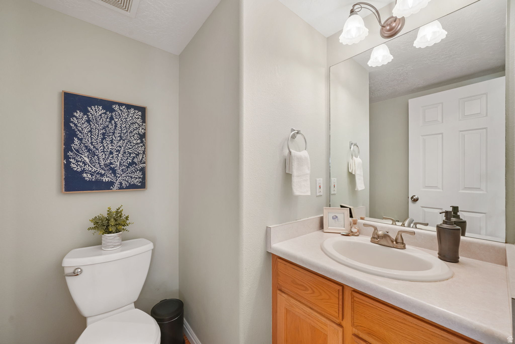 Bathroom featuring a wood-finish vanity with a laminate countertop, an oval undermount sink, and a framed mirror with a three-light fixture