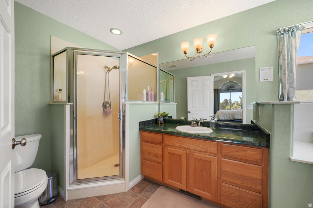 Bathroom featuring a glass-enclosed shower, a vanity with wood-finish cabinetry, and a countertop with an integrated sink
