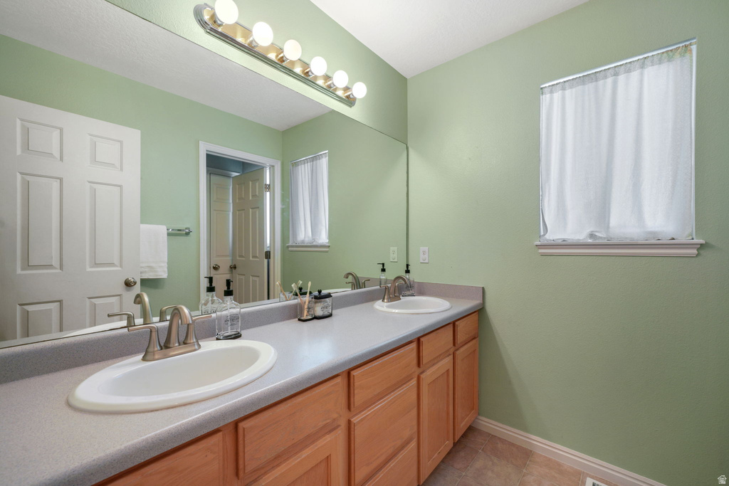 Bathroom vanity featuring dual undermount sinks, a light-toned countertop, and wood-finish cabinetry