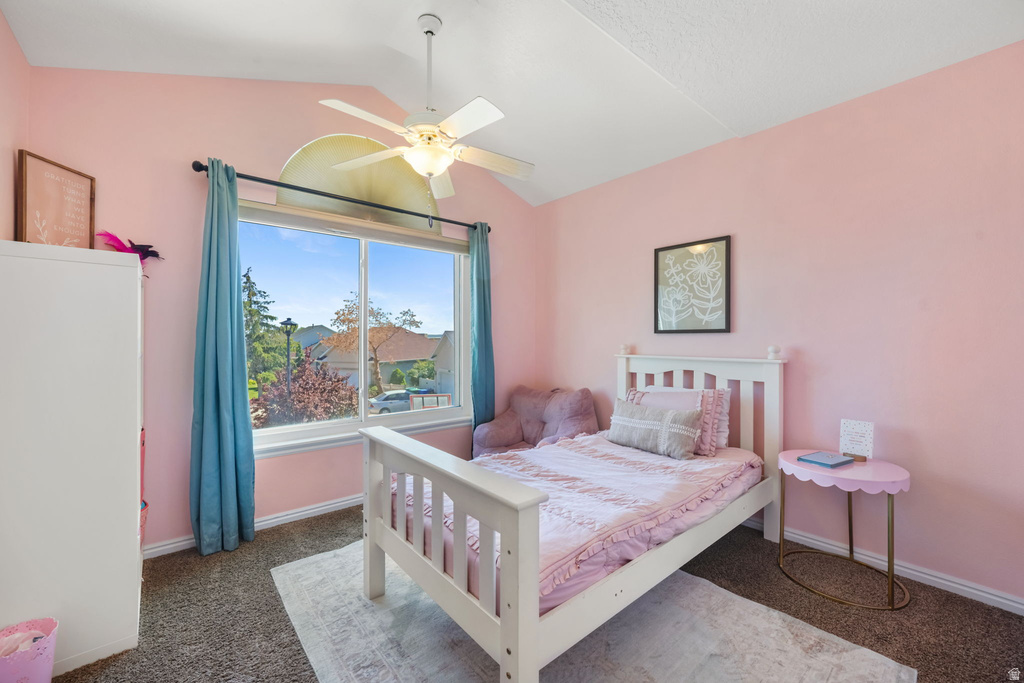 Vaulted ceiling room featuring a ceiling fan, large window with ample ambient light, and carpeted flooring
