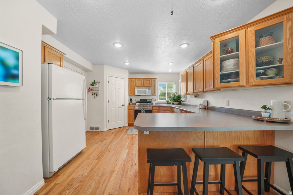 Kitchen featuring wood-finish flooring, wood cabinetry with some glass-front uppers, and recessed lighting