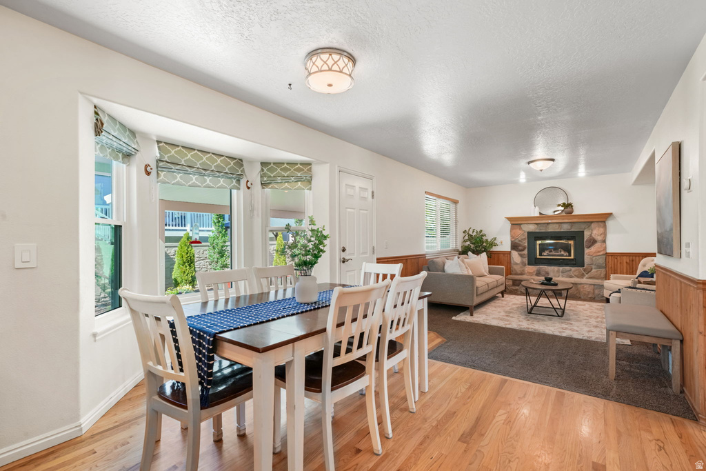 Open-concept living area featuring wood-finish flooring, a stone-faced fireplace with a wood mantle, and a bay window