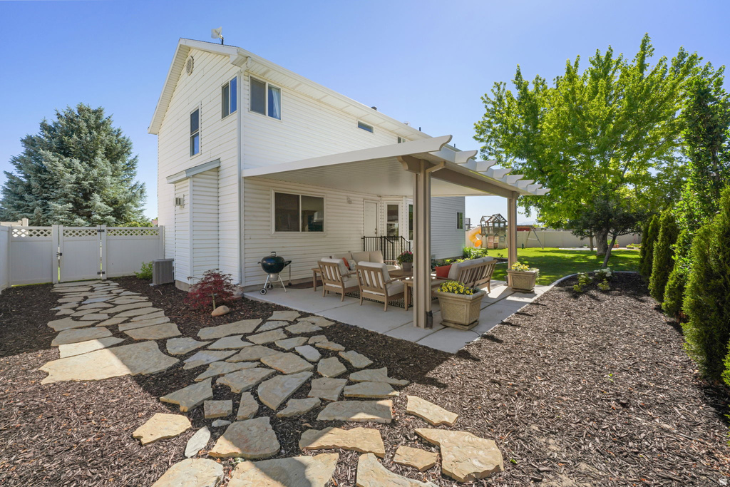Expansive backyard featuring a covered patio, flagstone pathway, mature landscaping, manicured lawn, and privacy fencing