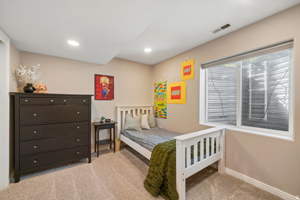 Carpeted room featuring a white window frame, recessed lighting, and a dark wood-finish dresser