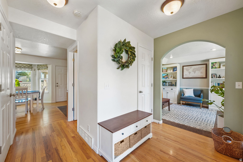 Welcoming entryway featuring warm wood-finish flooring, an arched doorway, and recessed ceiling lighting