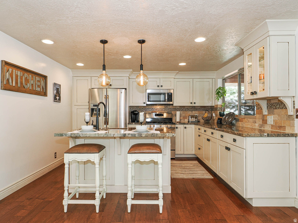 Open kitchen featuring a central island with countertop seating, recessed lighting, and pendant fixtures
