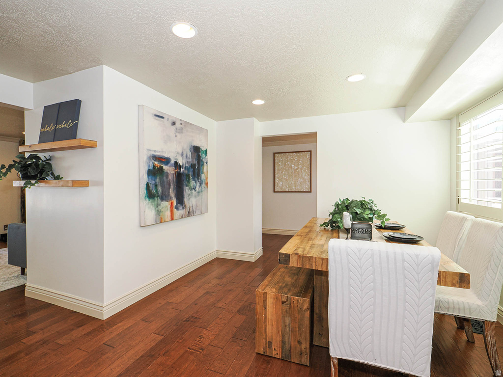 Dining area featuring rich wood-finish flooring, recessed lighting, white walls, and elegant baseboard molding