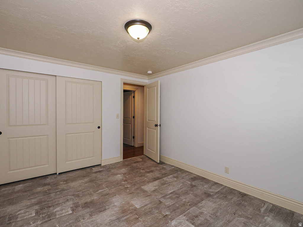 Spacious interior featuring wood-finish flooring, white walls, and crown molding