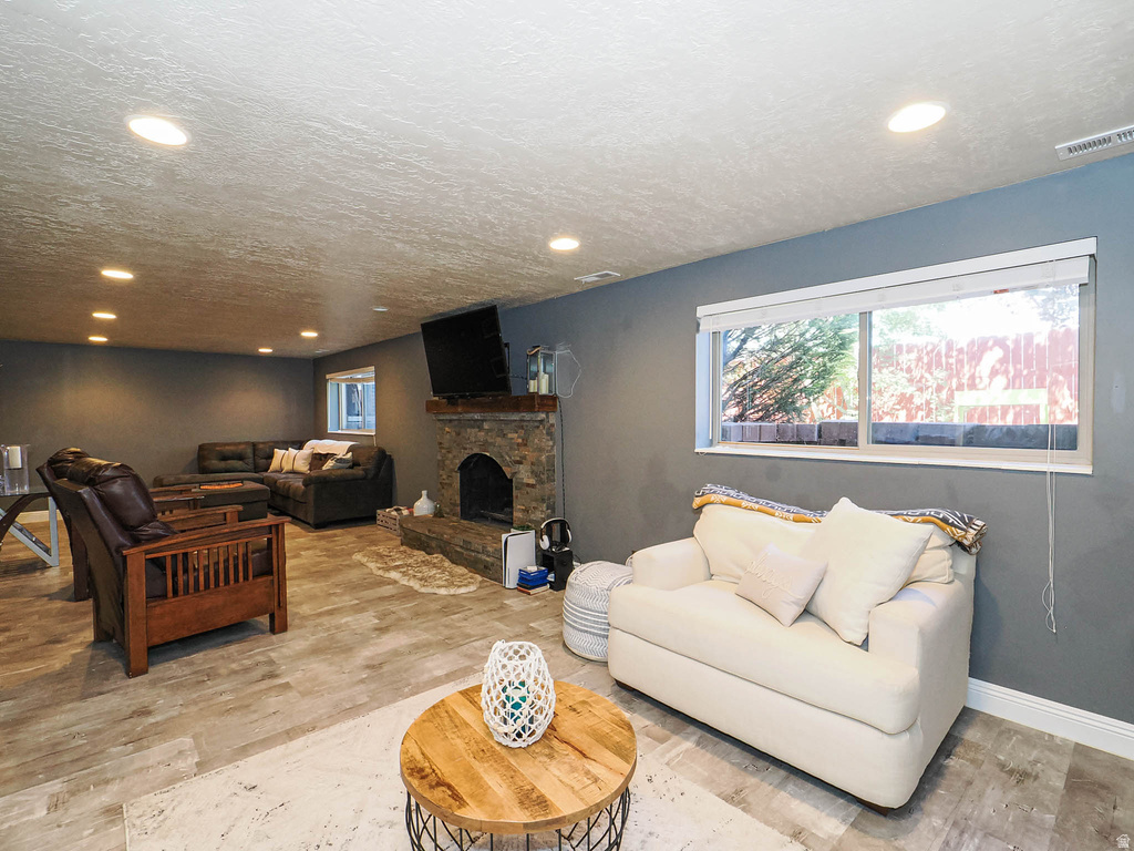 Spacious room featuring wood-finish flooring, recessed lighting, and a stone-clad fireplace with a wood mantel